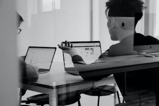 Mężczyźni w trakcie dyskusji, pracujący na laptopach