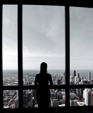 Kobieta spoglądająca przez okno wieżowca na widok miasta